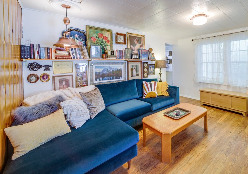 Living room with a blue velvet sectional and a wall of family pictures